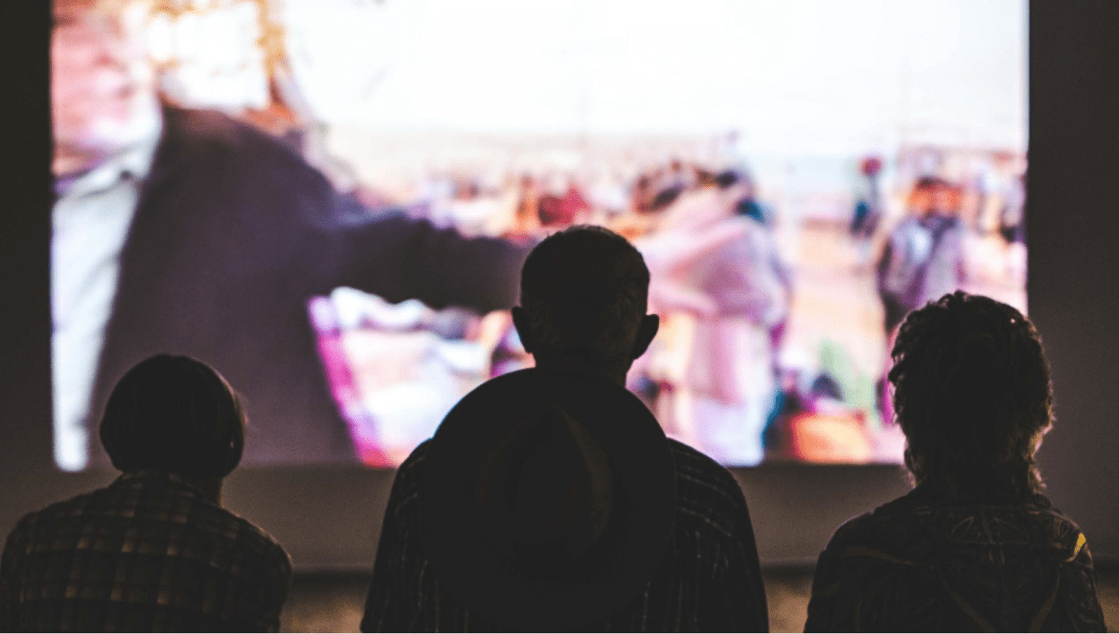 People watch a large outdoor movie screen