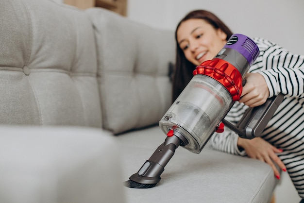 Woman doing housework with rechargeable vacuum cleaner