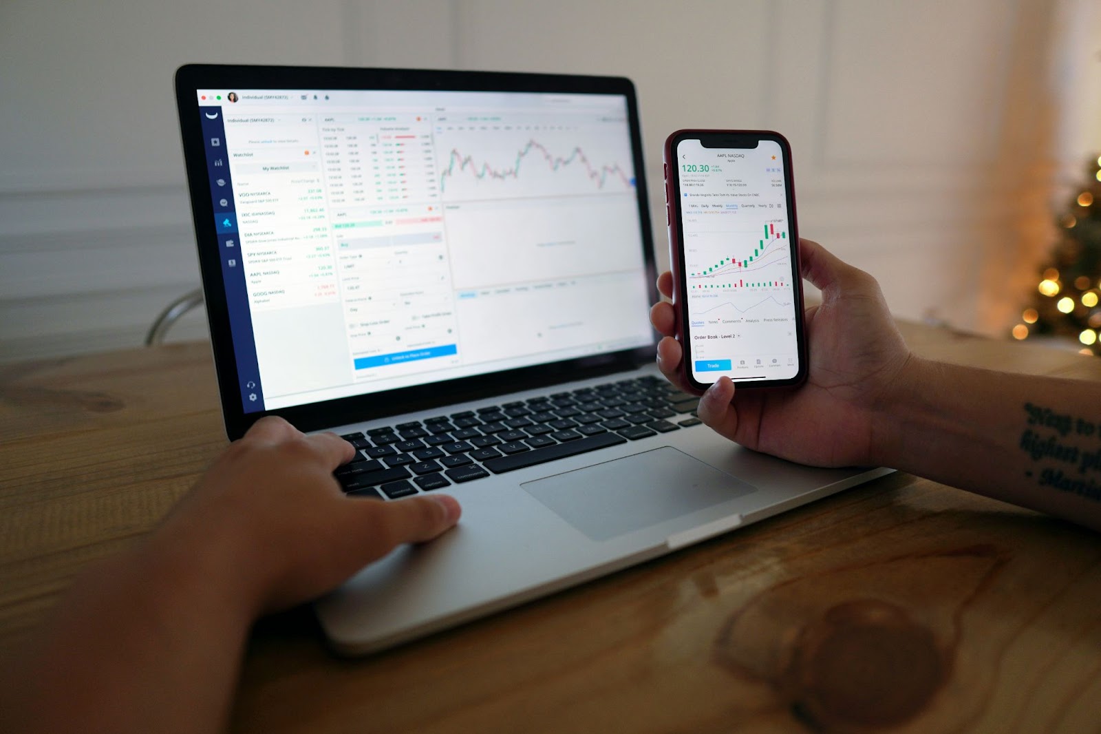 A person using a laptop and a smartphone to monitor stock market trends and investments