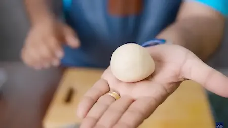 Dough balls being filled with sattu mixture and shaped into smooth balls.