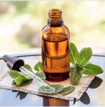 An open brown-colored bottle of an essential oil with green leaves