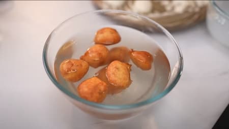 Preparing batter with urad dal, moong dal, bread soaked in milk, ginger, green chilli, jeera, salt, and raisins for Dahi Bhalla. Frying until golden brown, soaking in hing water, and topping with curd mixture.