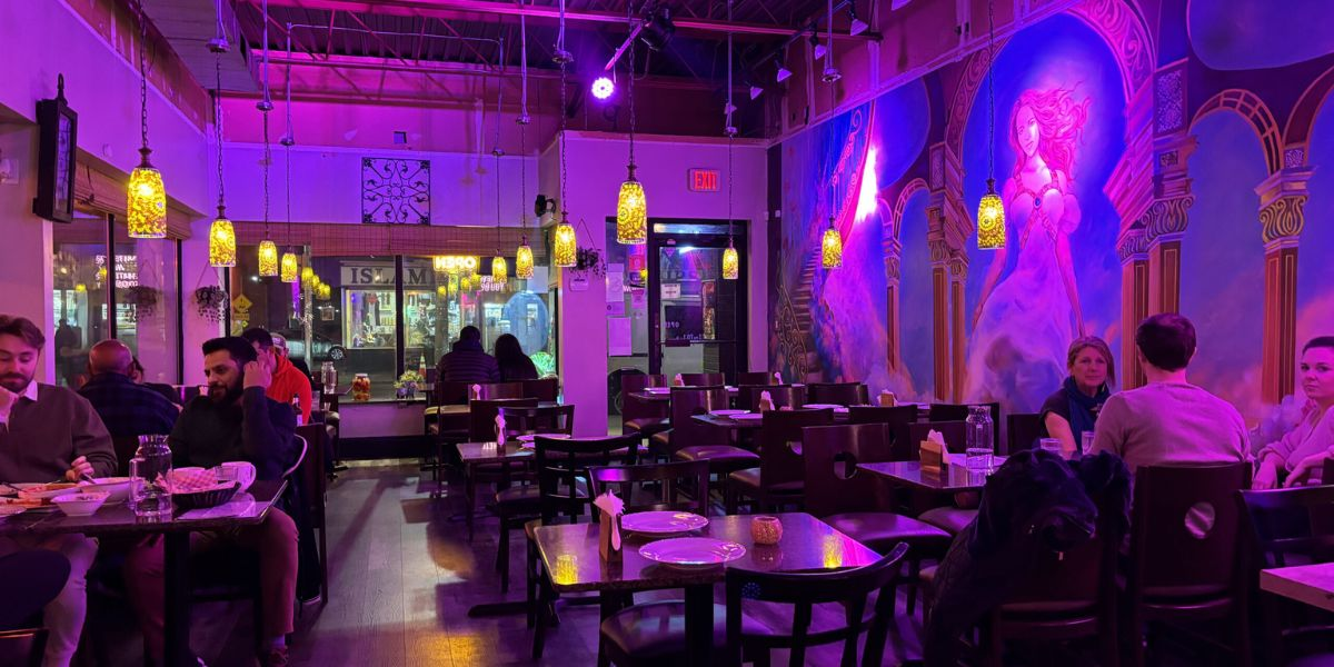 People sitting at tables in a restaurant with purple lighting.