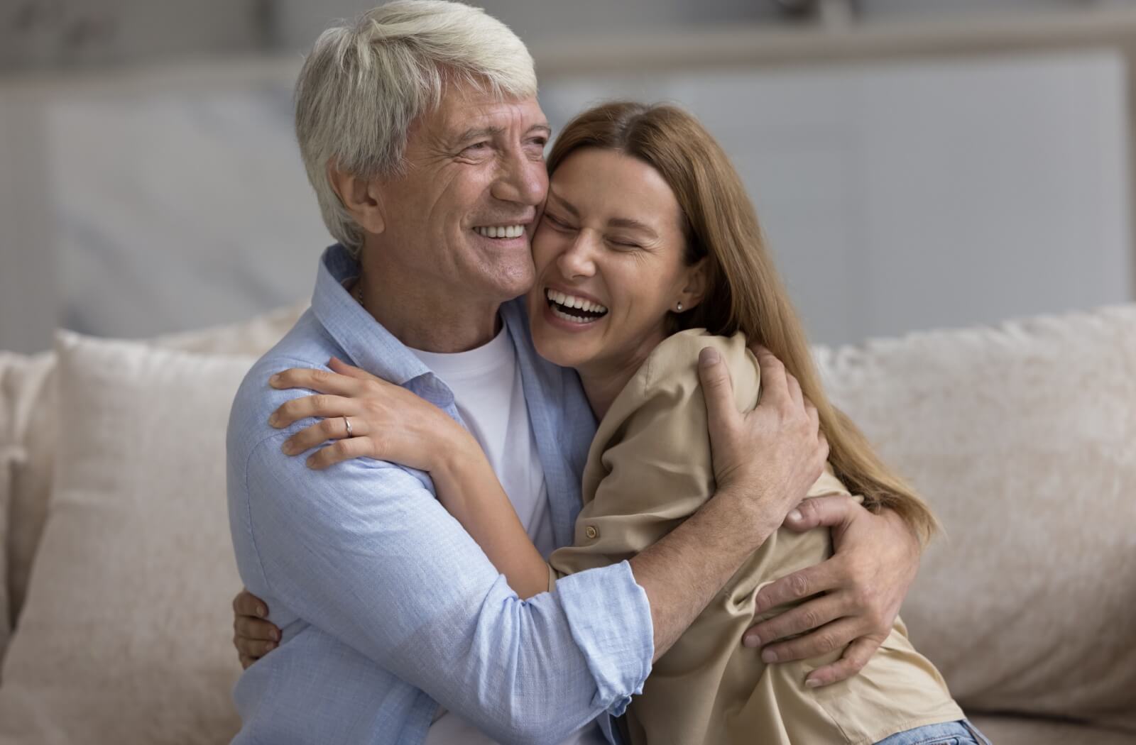 A happy young woman hugging her happy older adult father.