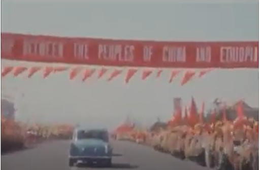 A car driving on a road with a banner above it Description automatically generated
