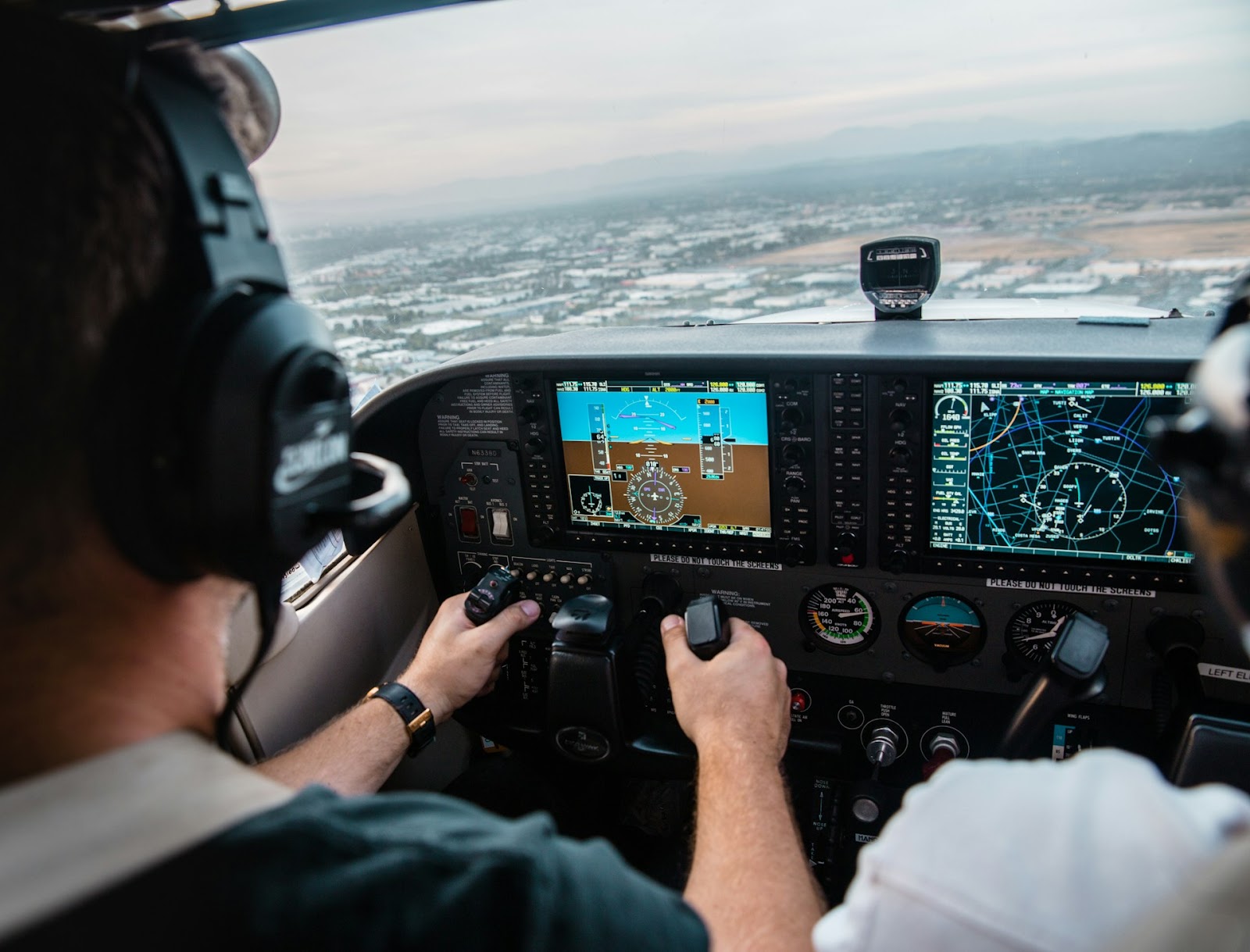 Two pilots inside an airplane's cockpit, getting ready to fly.