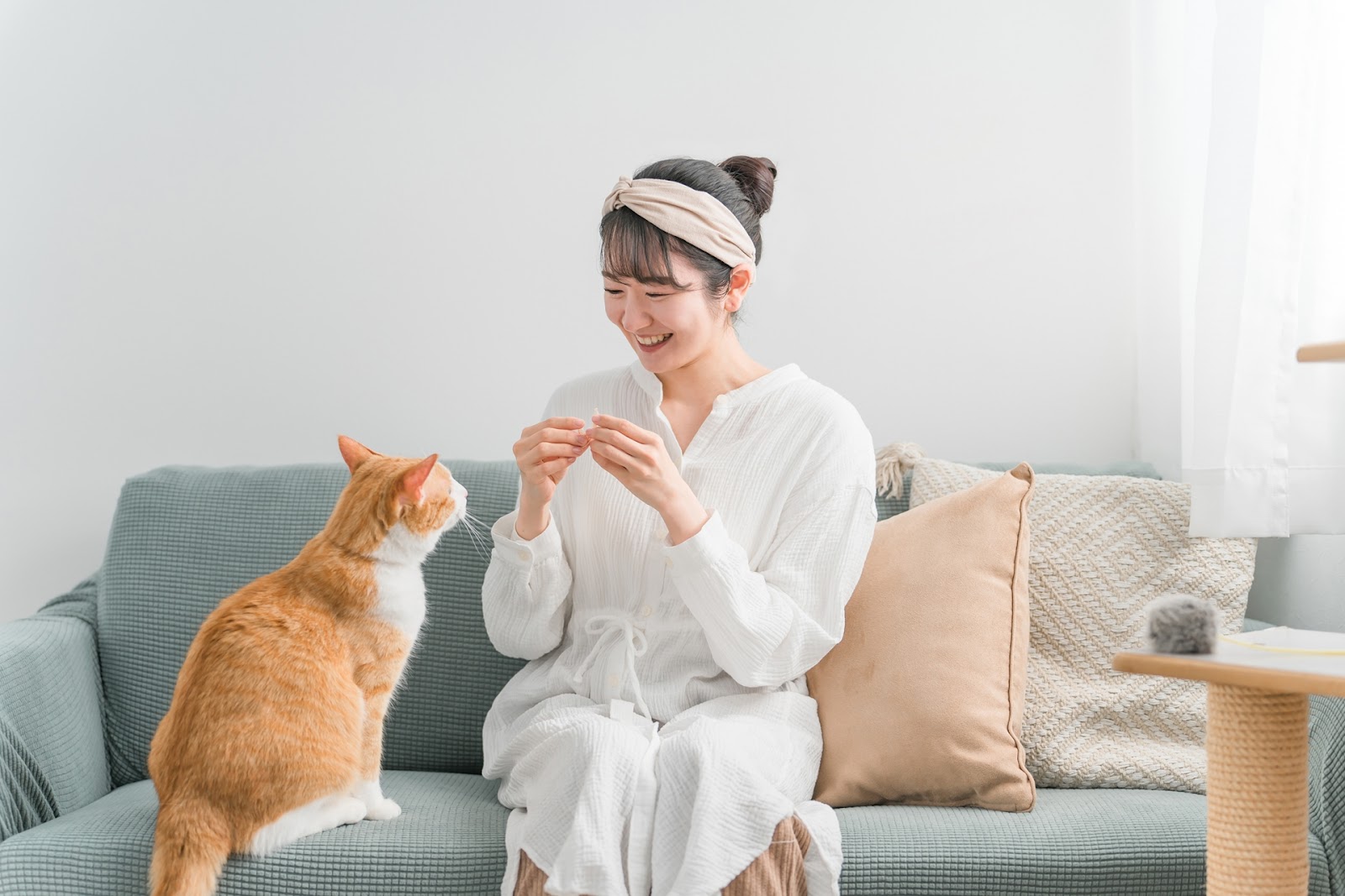 ソファで猫におやつをあげる女性