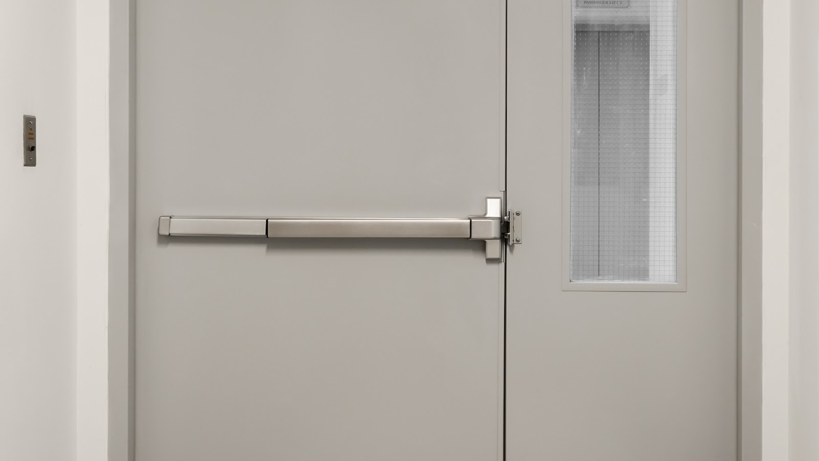 A business building features a securely installed panic bar on an exit door.