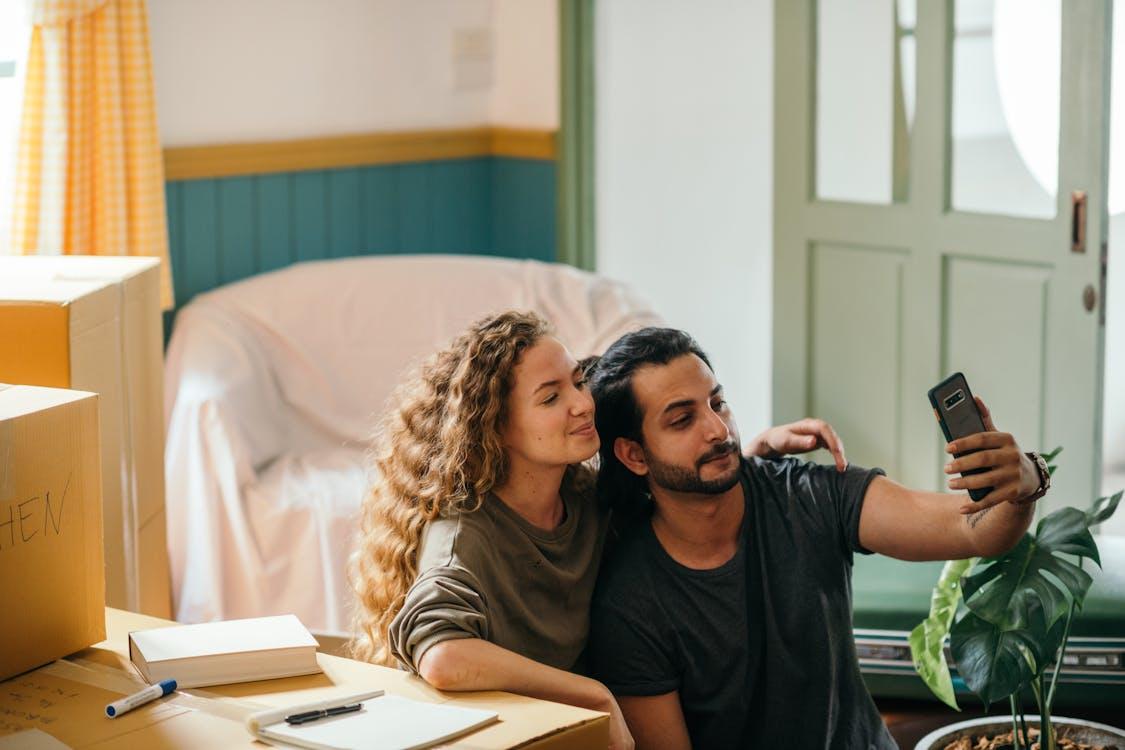 Free Cheerful young couple taking selfie with smartphone while moving Stock Photo