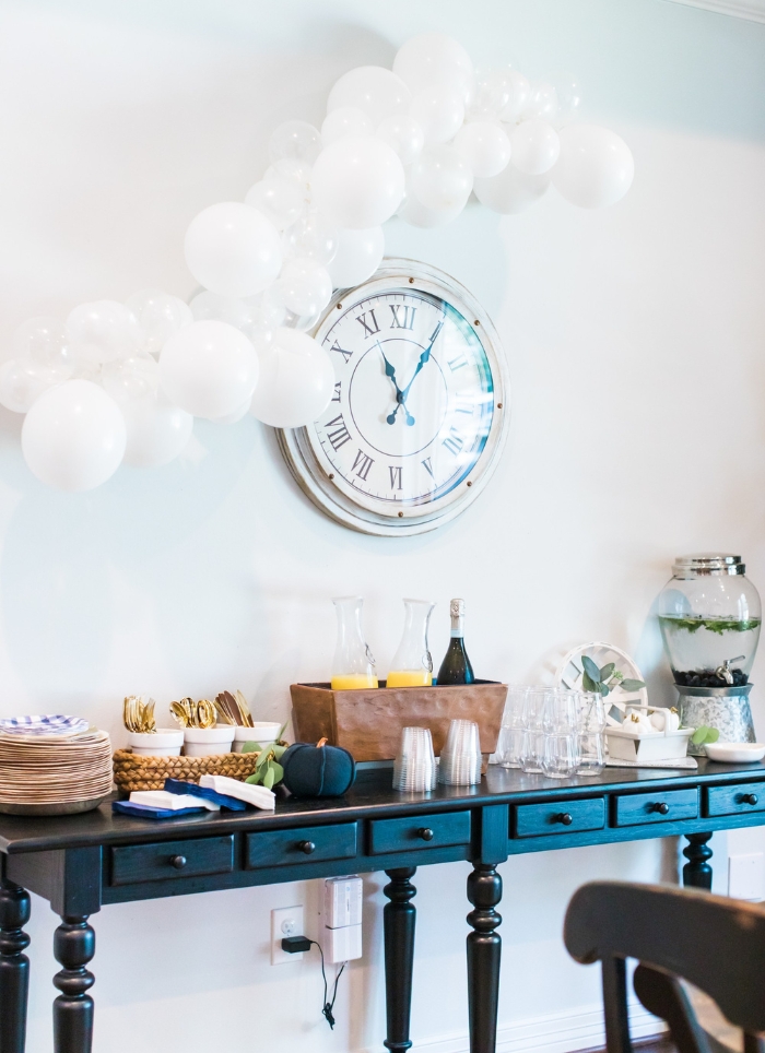clock hanging over side table with party food