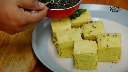 Pouring the tempering over the steamed Dhokla.