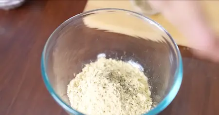 Sattu flour mixture with chopped onions, garlic, ginger, green chillies, and coriander being mixed in a bowl.