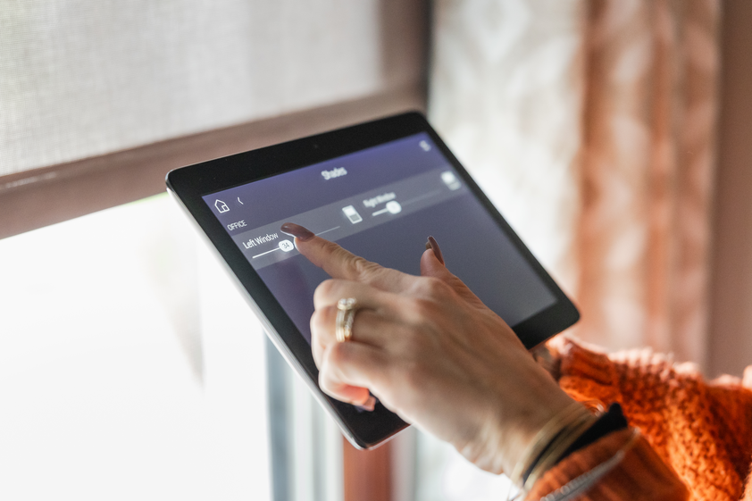 Woman using tablet to control window shades