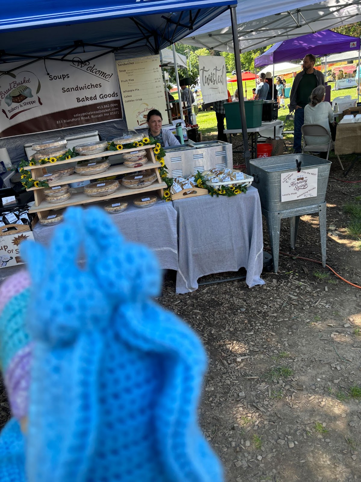 A blurry blue snail in front of a market stand selling fresh pies