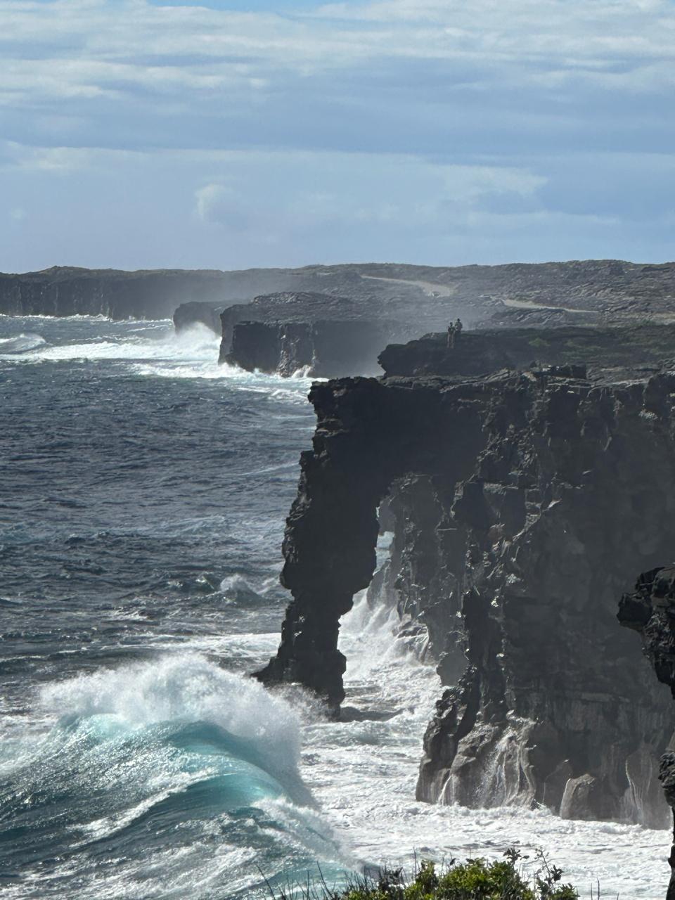 A rocky cliff with waves crashing on it

Description automatically generated