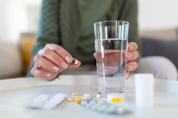 Free photo senior woman takes pill with glass of water in hand