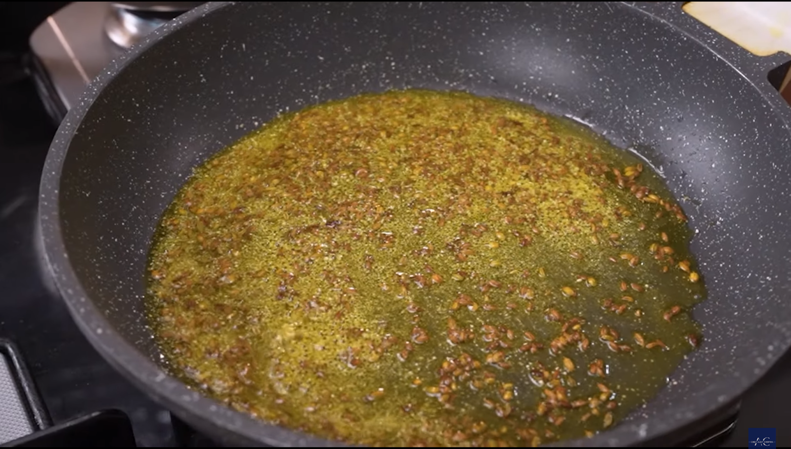 Heating mustard oil with cumin and fennel seeds to prepare the spice base for Mirch Ka Instant Achar.