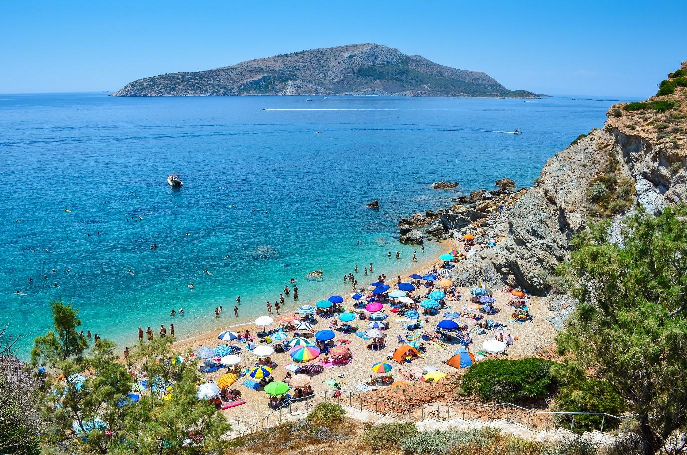 A beach with many umbrellas and people on it

Description automatically generated