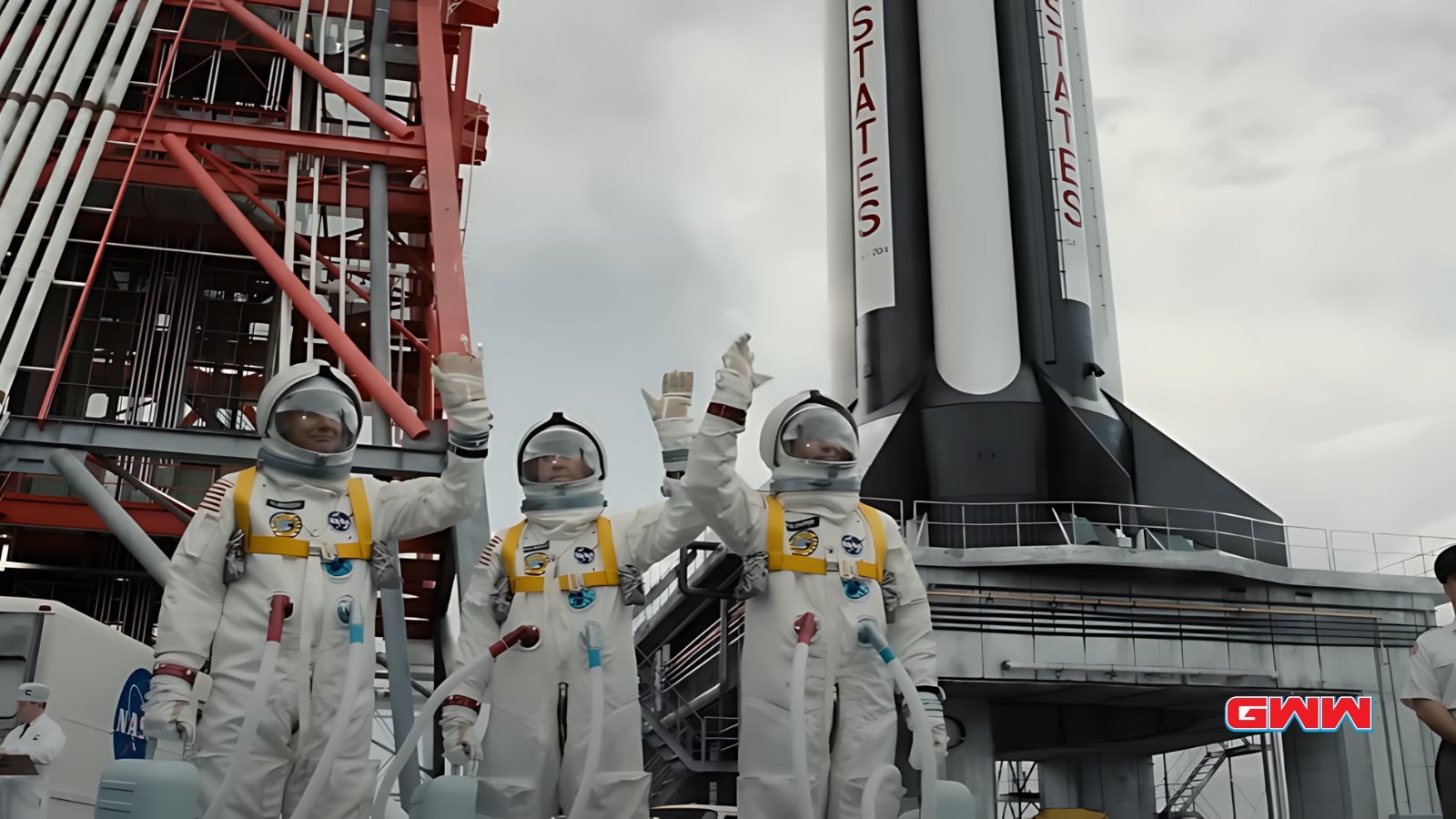 Neil, Buzz y Michael en trajes espaciales saludando cerca de un cohete.