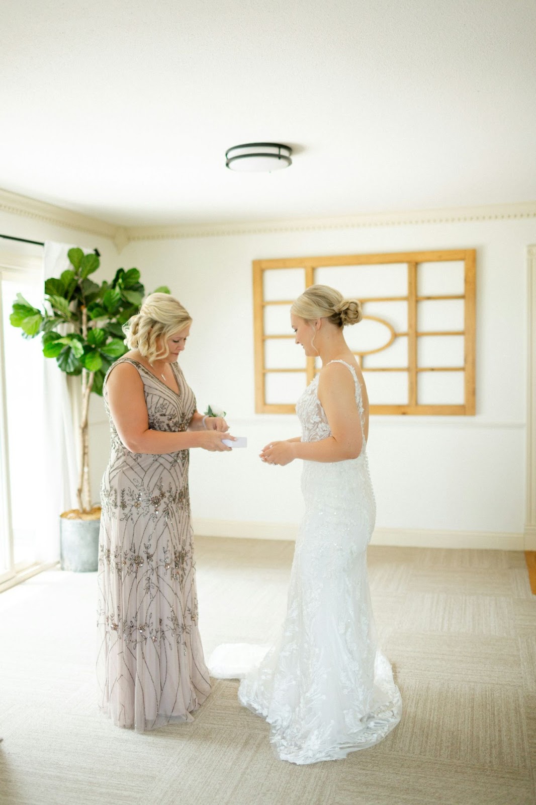 A bride receiving a gift on her wedding day from her bridesmaid or mother.