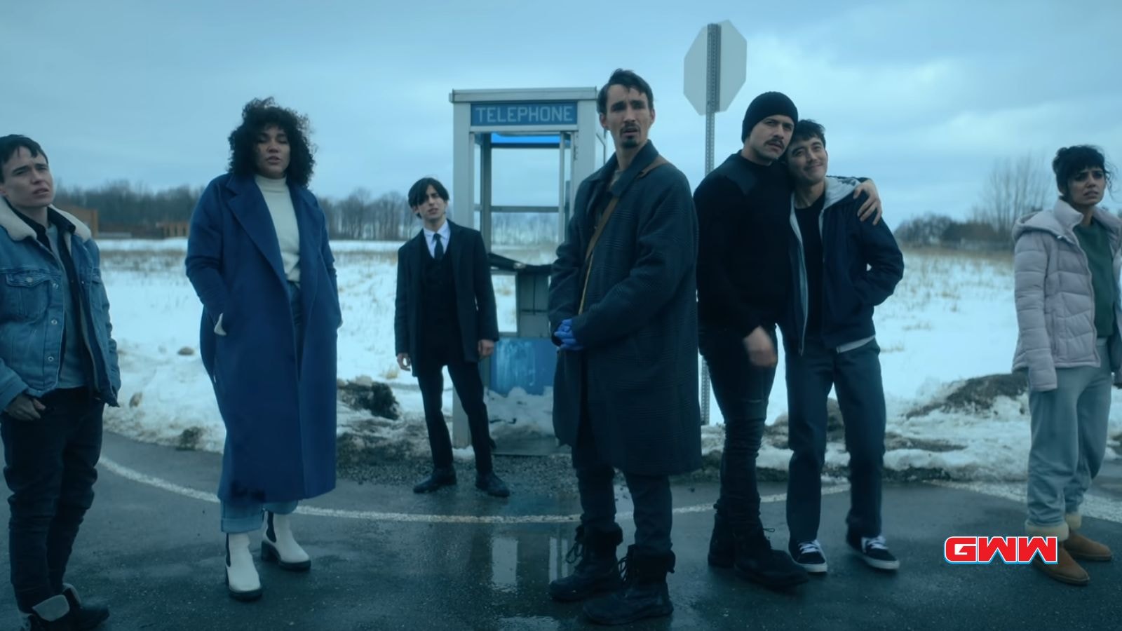 Hargreeves family standing by a phone booth in a snowy landscape.