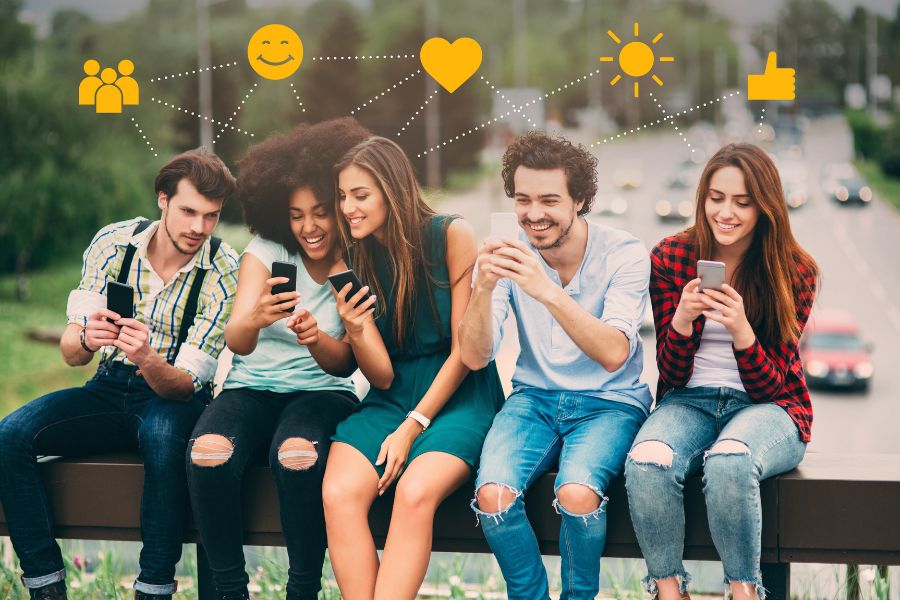 Friends sitting outdoors, using phones with social media icons above them.