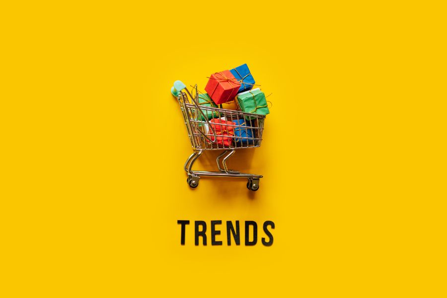 Mini shopping cart with colorful gifts, 'Trends' text on yellow background.