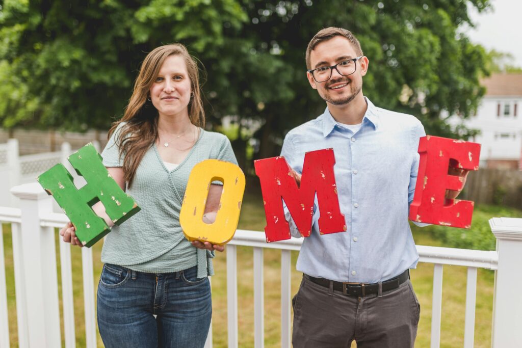 man and woman holding home sign