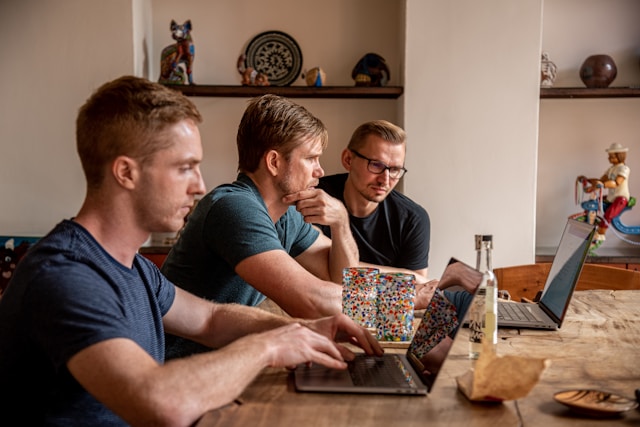 Group of employees working on a table with laptops.