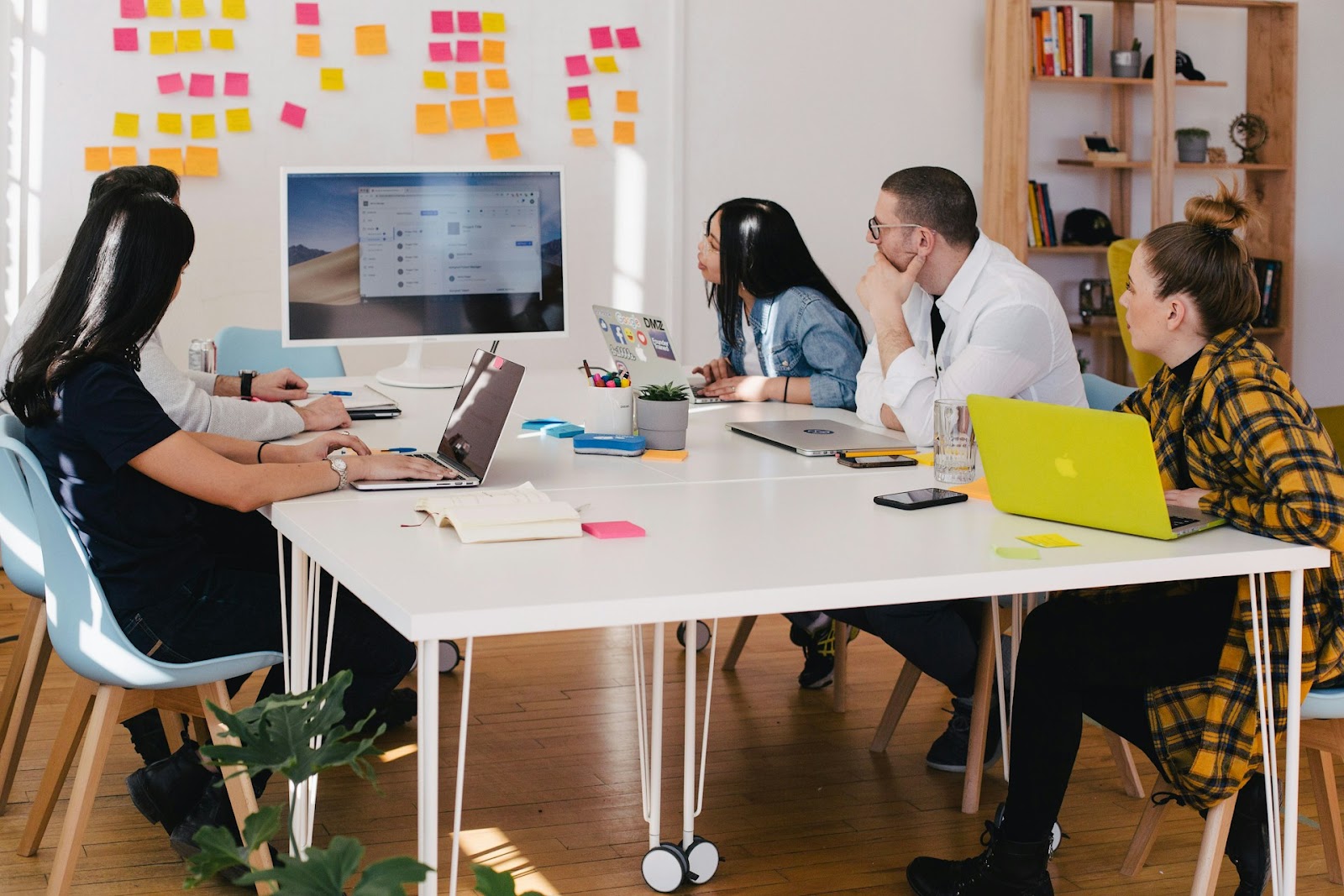 A team of professionals sitting together at a table with laptops brainstorming or working on a project.