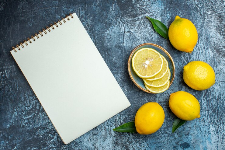 Top view of lemons, leaves, and a spiral notebook for an invisible ink STEM activity.