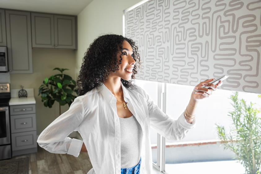 Woman next to patterned shades with remote in her hand