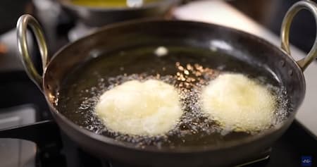 Frying Malpua in ghee until golden brown.