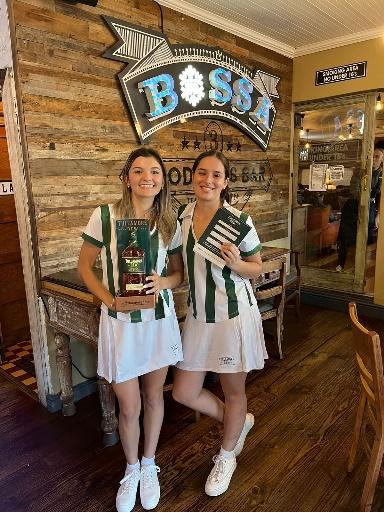 Two women holding awards in front of a sign

Description automatically generated