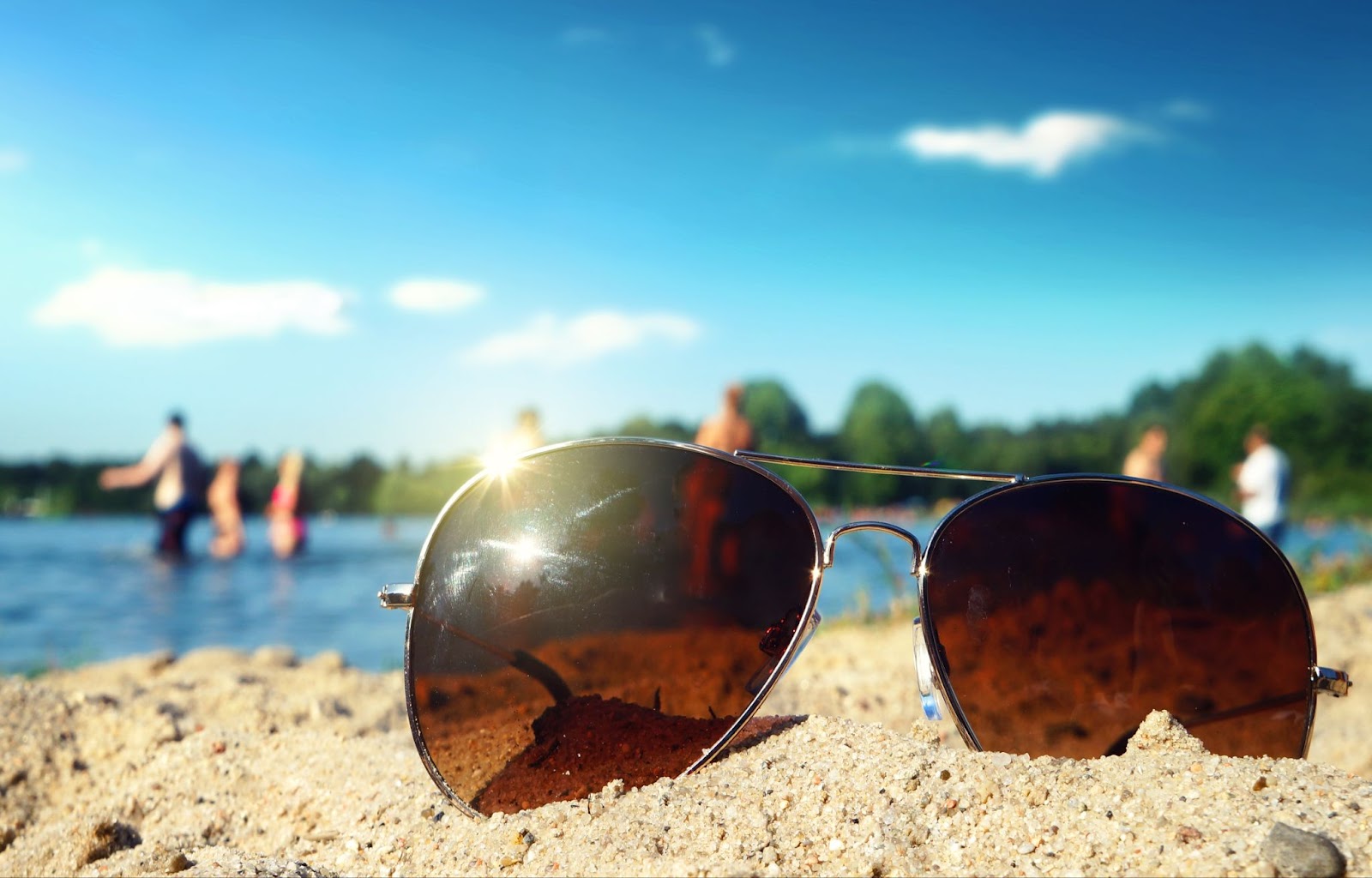 a pair of glasses are left in the sand at the beach, making the owner more at risk of an eyeball sunburn.