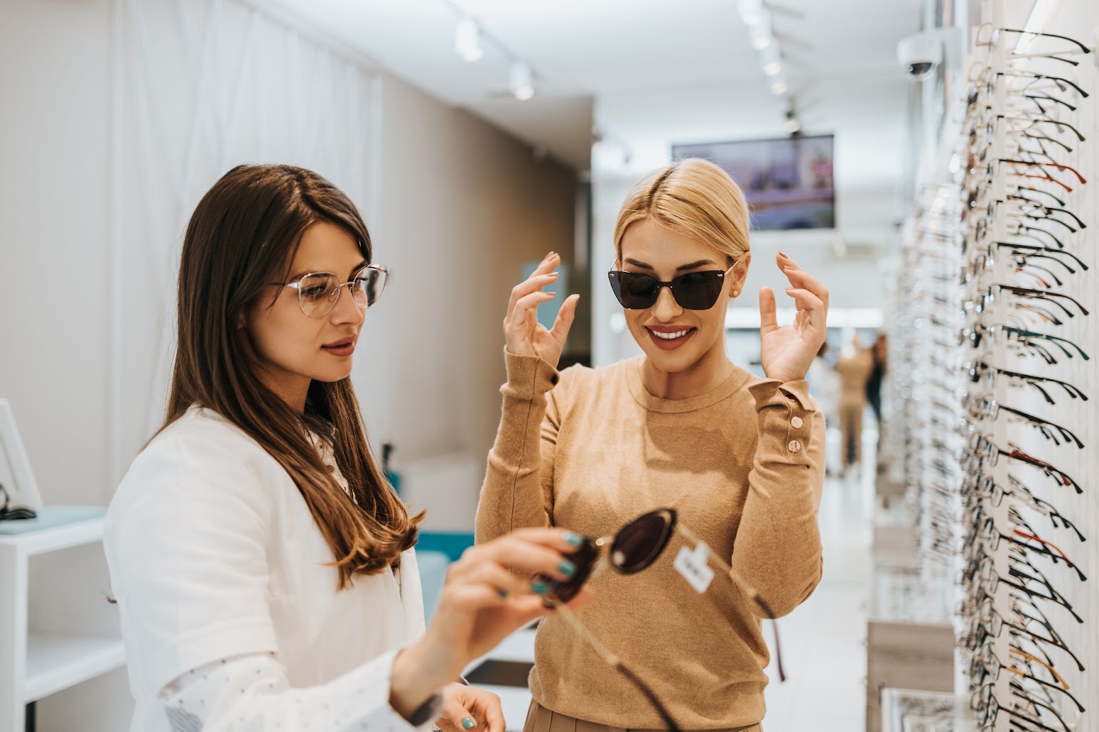 A smiling young woman working with her optometrist to find the right pair of sunglasses.