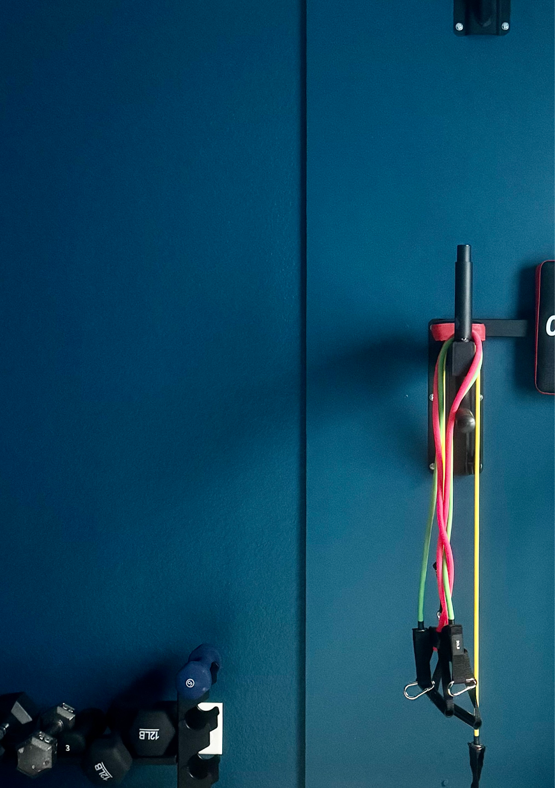 A Benjamin Moore Slate Teal wall is pictured in a basement home gym. 