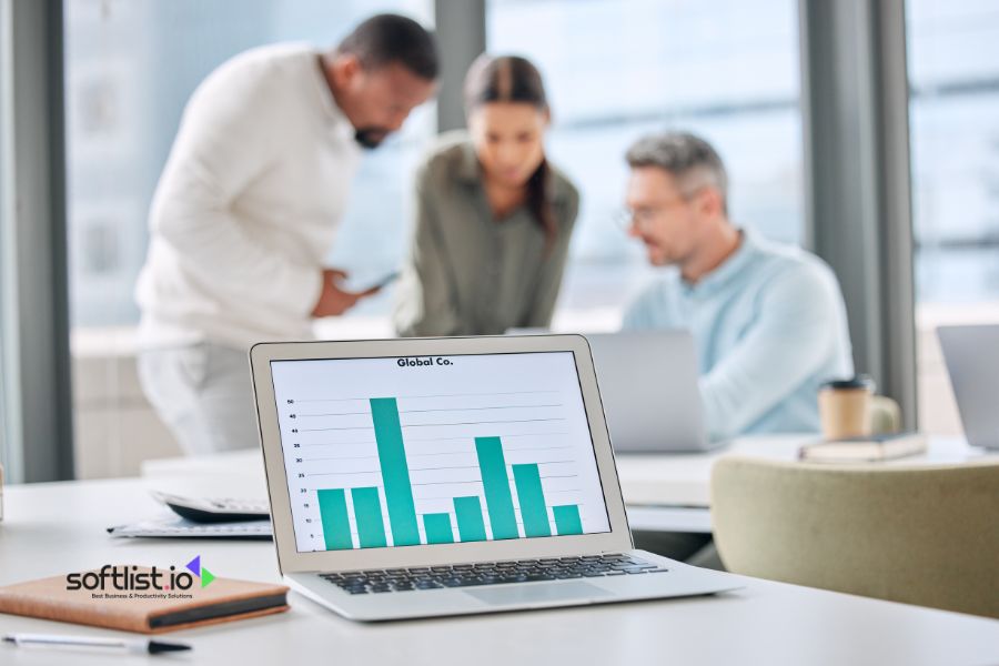 Business team working on laptops with a bar graph on screen.