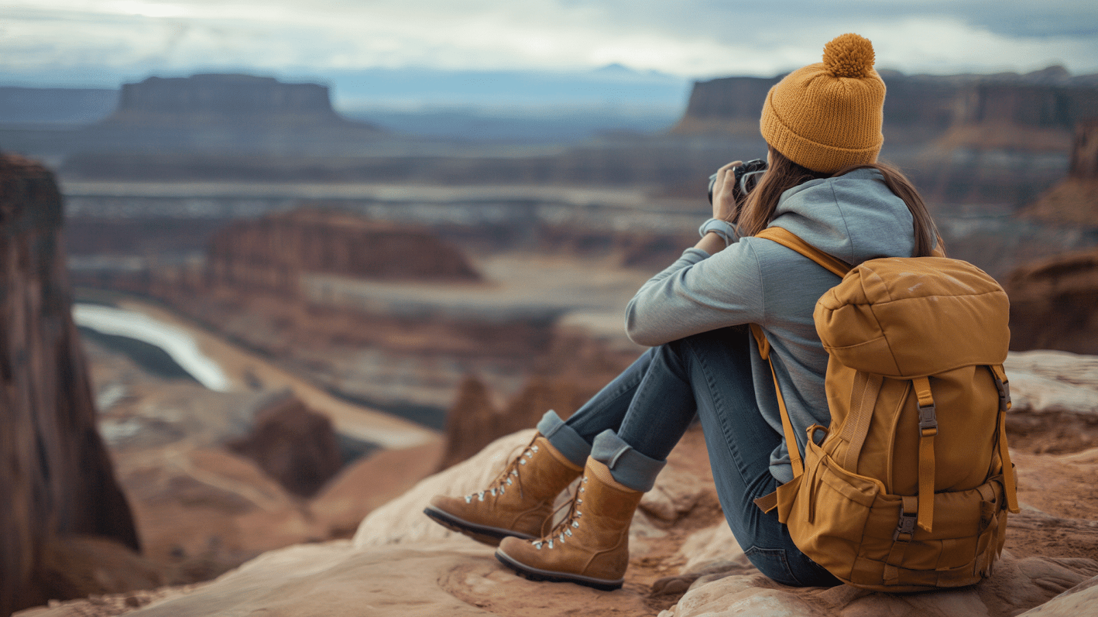 A solo traveler photographing a canyon landscape from a cliff
