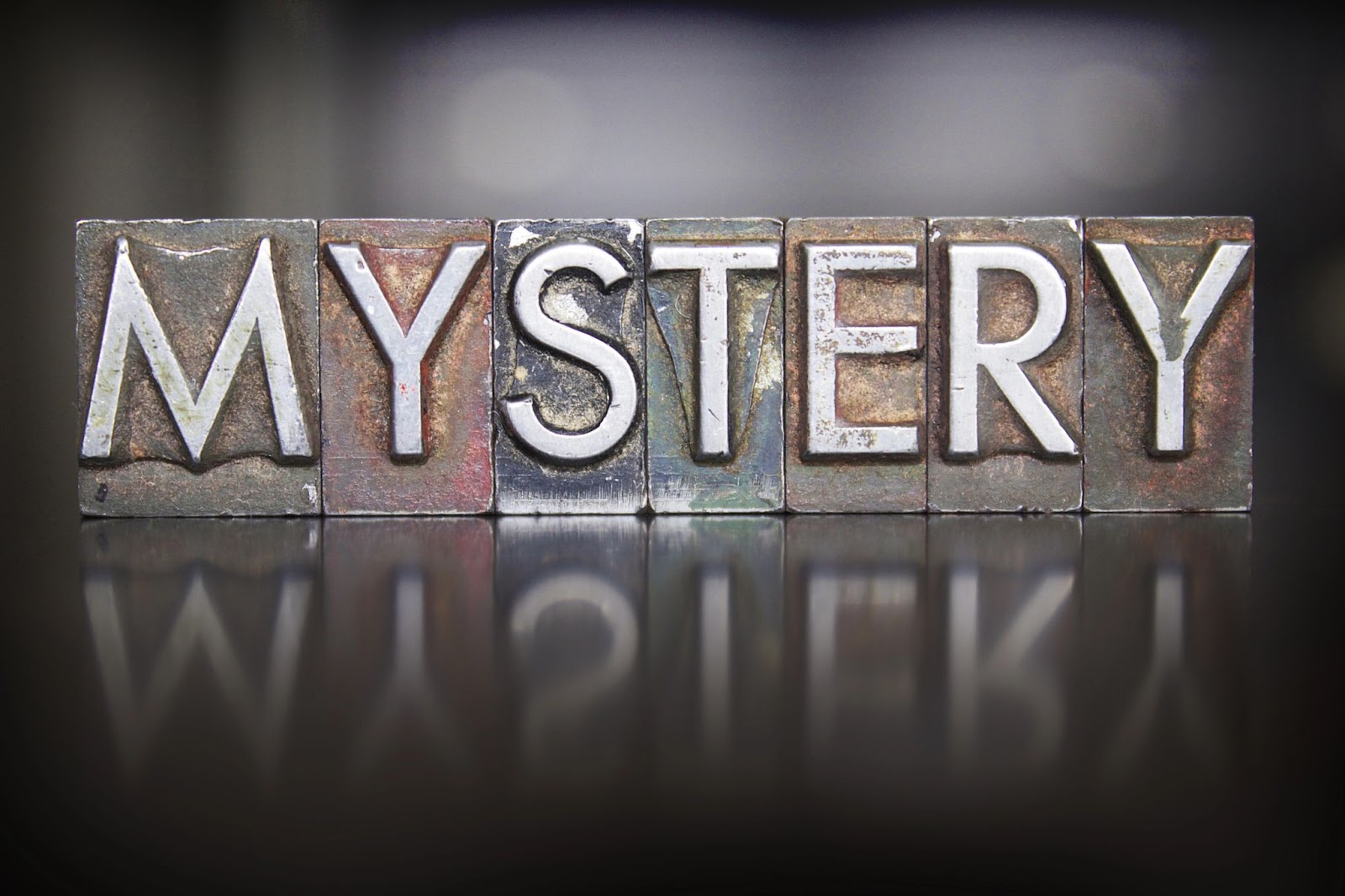 (Block letters spelling "MYSTERY" arranged on a reflective surface with a dark background, symbolizing the essence of problem-solving as a key skill.)