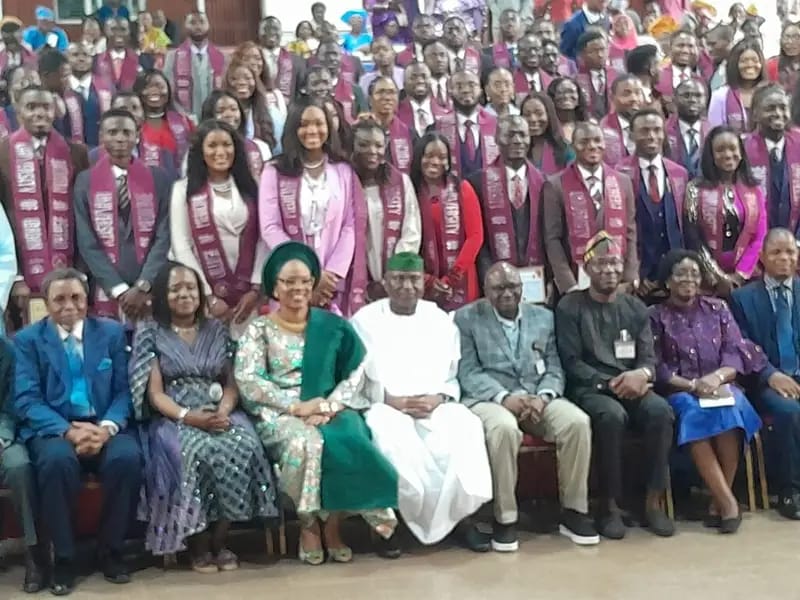 A group photo of the graduates standing behind a row of seated guests 