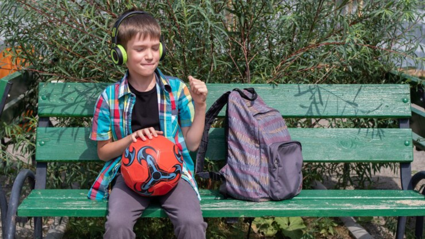 Bagsglobal | Boy sitting with kids sports bags and a basketball in hand