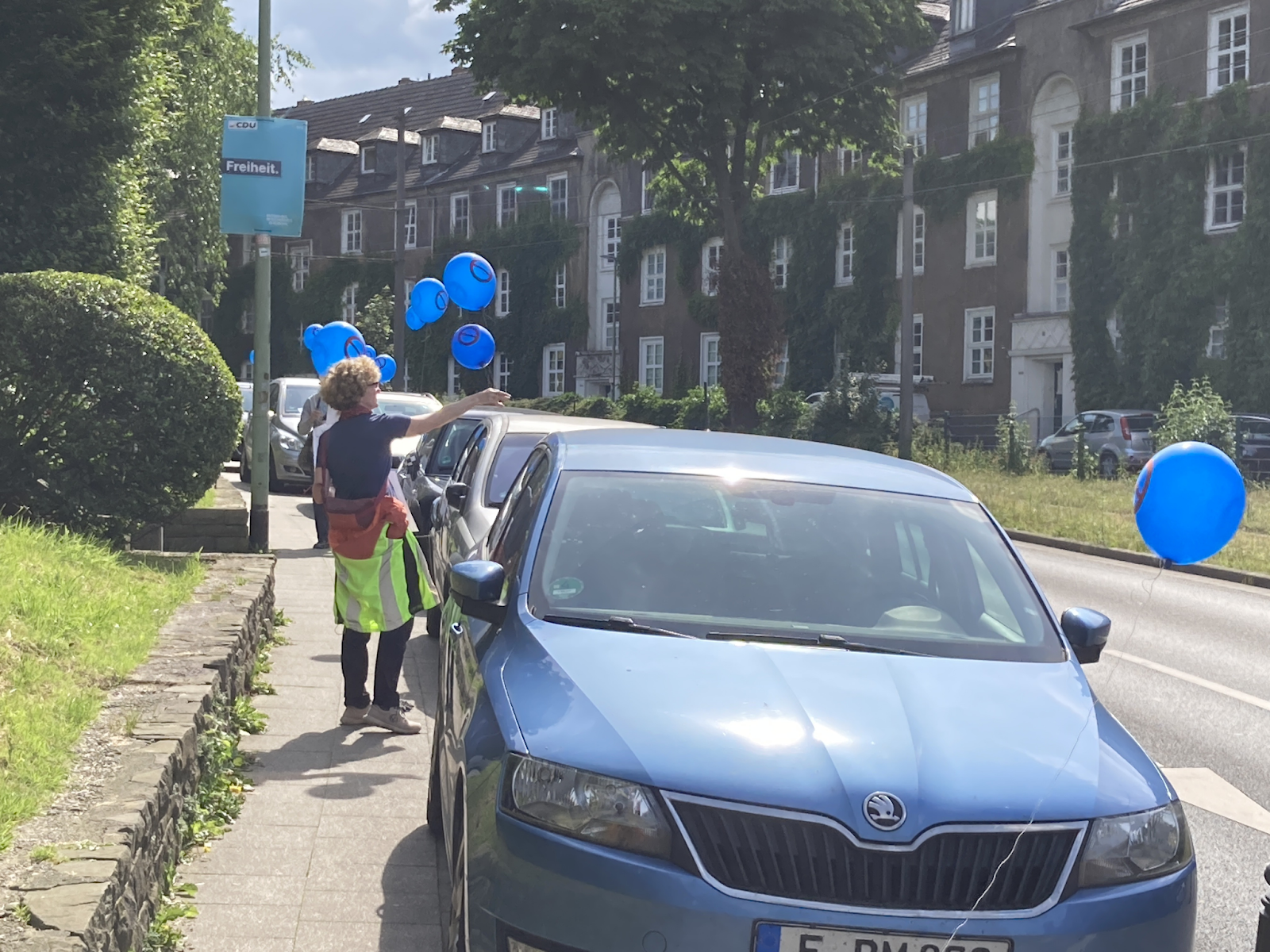 Viele blaue Ballons zeigen falschparkende Autos entlang der Sommerburgstraße an