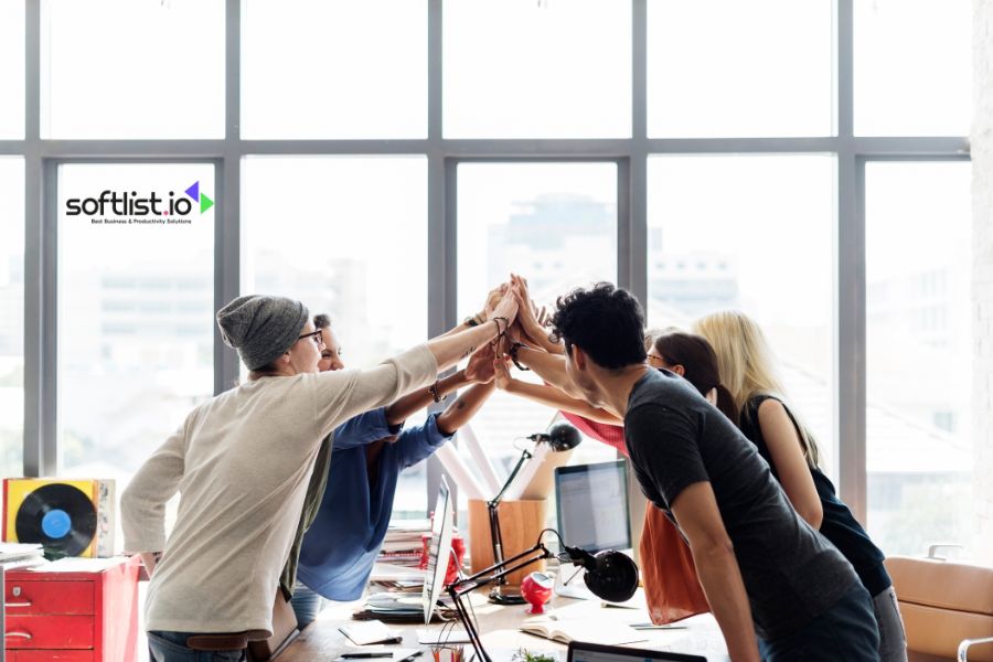 Group of colleagues celebrating success with a high-five in office.