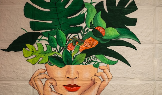 Artwork painted on a brick wall showing plants growing from woman’s head