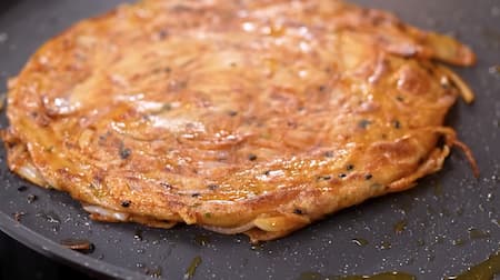 Cooking the rolled Onion Laccha Paratha on a hot tawa until golden brown and crispy on both sides.