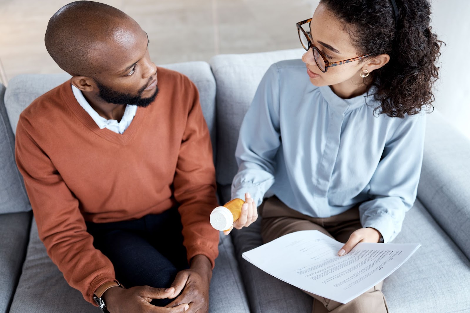 A female psychologist explains the pill intake to the male patient. 