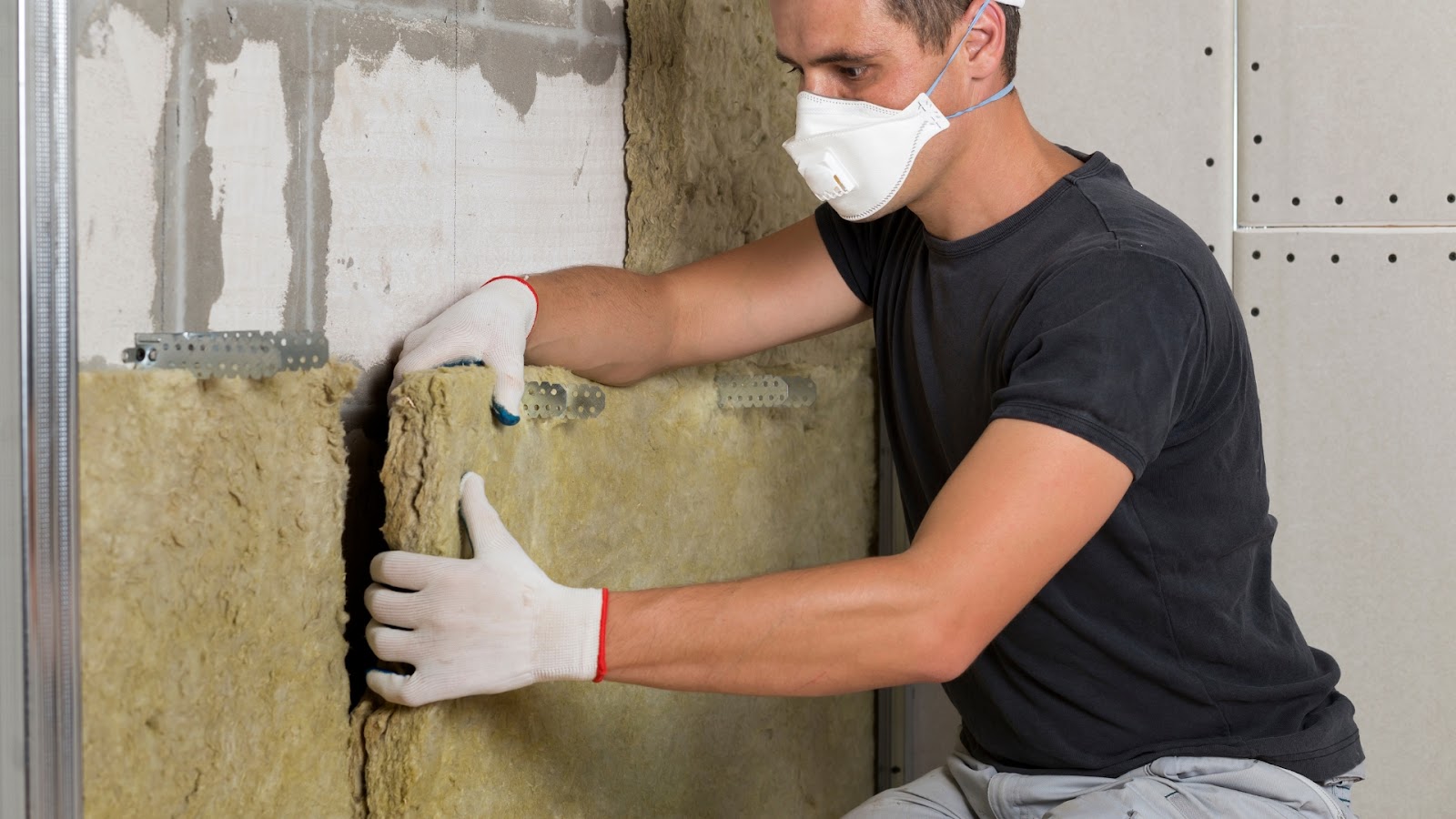 A man installing a garage door insulation made from fiberglass batts