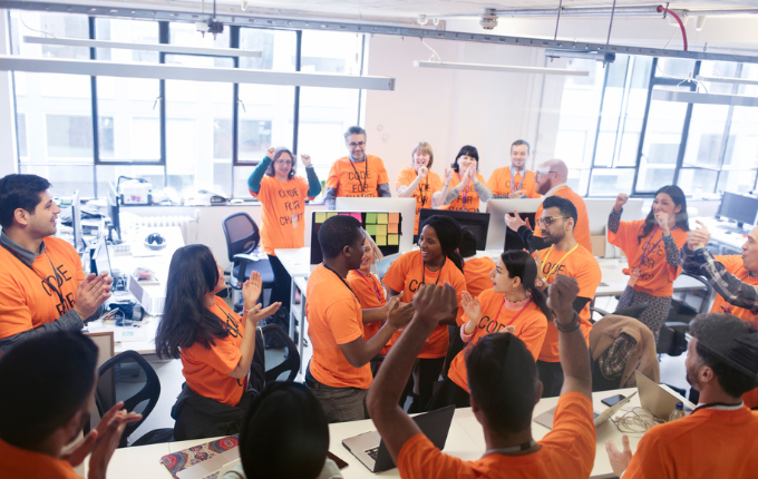 A group of people clapping and cheering due to the success of their t-shirt fundraiser.