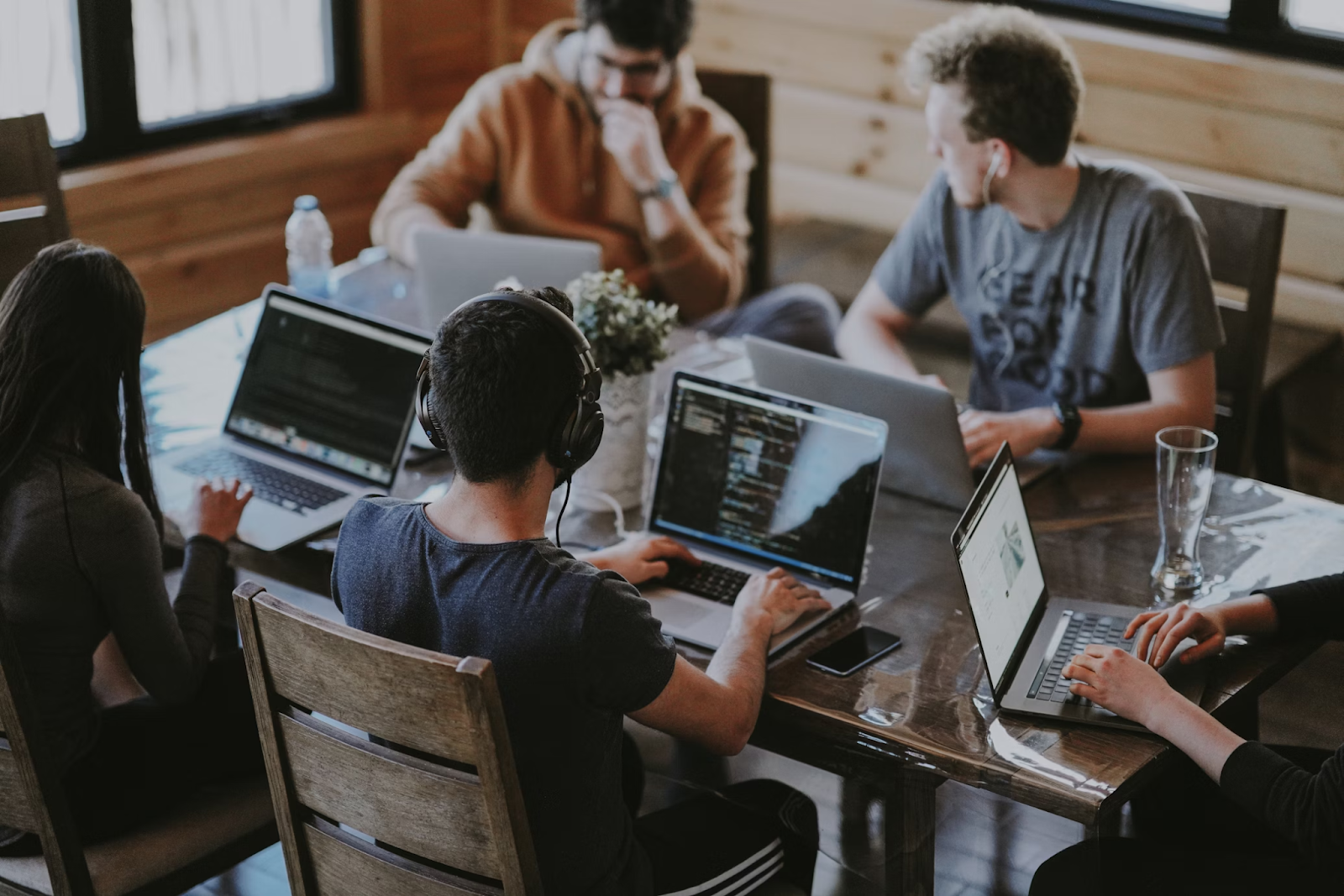 Group of people working on laptops around a table.